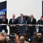 Mexican-government and Safran officials in a horizontal line preparing to cut a ribbon launching a new assembly line at Safran's aerospace parts manufacturing plant.