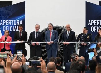 Mexican-government and Safran officials in a horizontal line preparing to cut a ribbon launching a new assembly line at Safran's aerospace parts manufacturing plant.