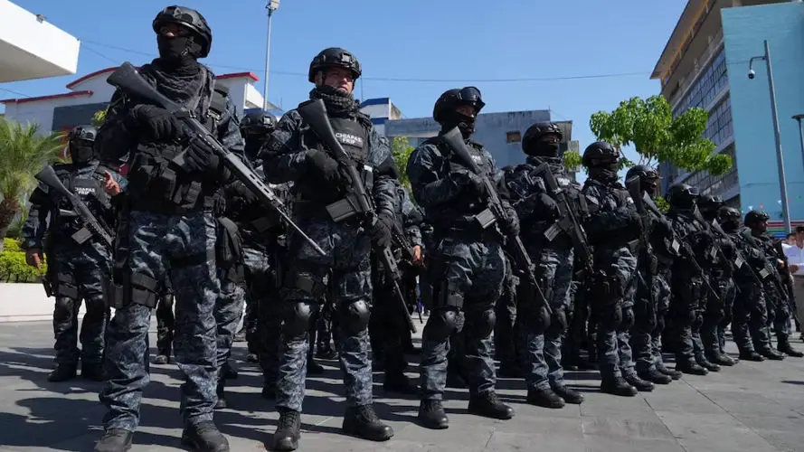 A lineup of the FRIP special forces state police in Chiapas, wearing black military-style police uniforms and carrying machine guns at their sides.