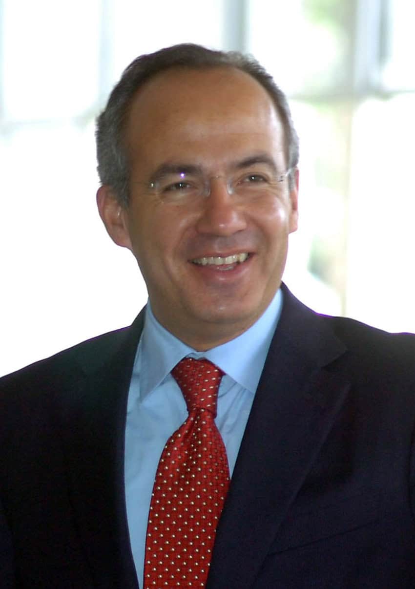 Former Mexican president Felipe Calderon in a suit smiling for a photo against a bokeh background.