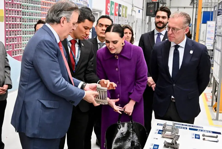 Mexico's Economy Minister Marcelo Ebrard holding an engine part while other officials look on at a Safran México plant in Queretaro.