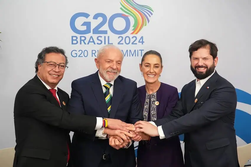 From left to right, President Gustavo Petro of Colombia, President of Brazil Luiz Inácio Lula da Silva, President of Mexico Claudia Sheinbaum and President of Chile Gabriel Boric stand in front of a wall with the 2024 G20 Leaders Summit logo on it. They are standing side by side, smiling, with their hands on top of one another to show unity.