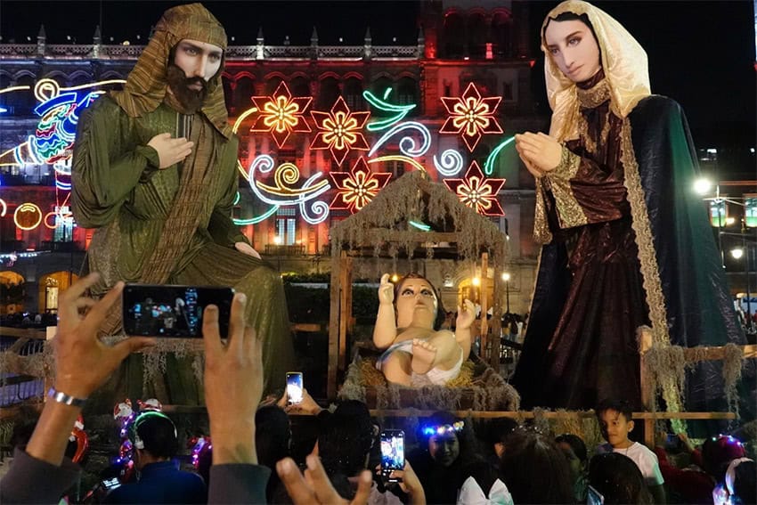 A crowd takes pictures of a giant baby Jesus statue next to Mary and Joseph statues, at Mexico City's Christmas Verbena.