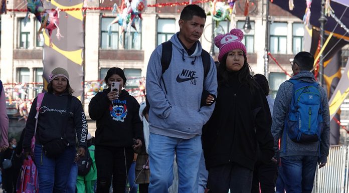 Mexico City residents in sweaters and warm hats walk through the city amid a cold front