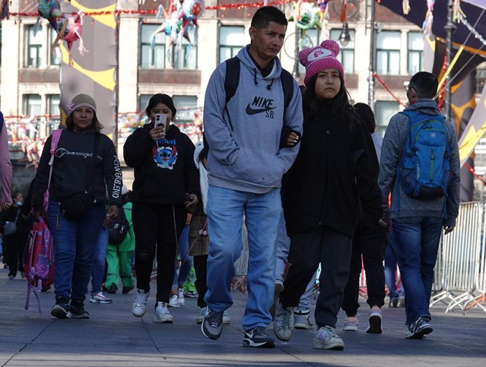 Mexico City residents in sweaters and warm hats walk through the city amid a cold front