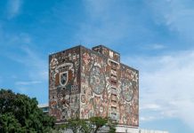 The National Autonomous University of Mexico library in Mexico City, a concrete building whose top floors is painted with the university logo and with a mural of images related to Mexico's indigenous history