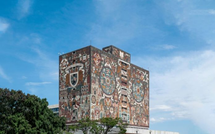 The National Autonomous University of Mexico library in Mexico City, a concrete building whose top floors is painted with the university logo and with a mural of images related to Mexico's indigenous history