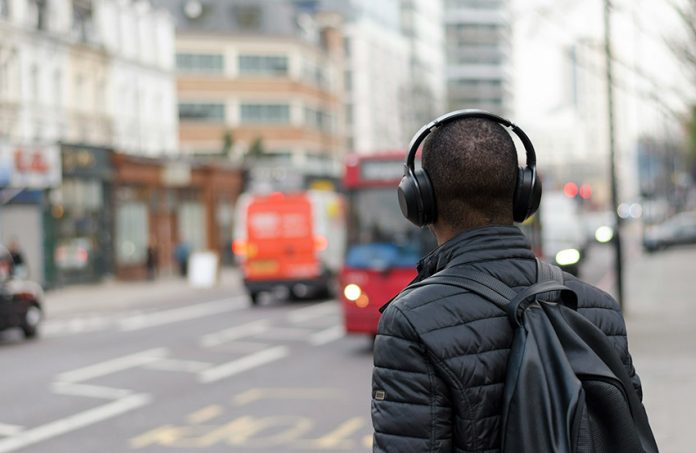 A man listens to headphones in a city, to illustrate the best Mexican msuic and podcasts of 2024