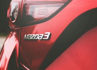 Closeup of the back of a red Mazda car with the Mazda 3 logo on it .