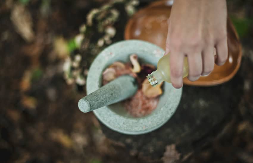 A person preparing a massage mix in a molcajete.