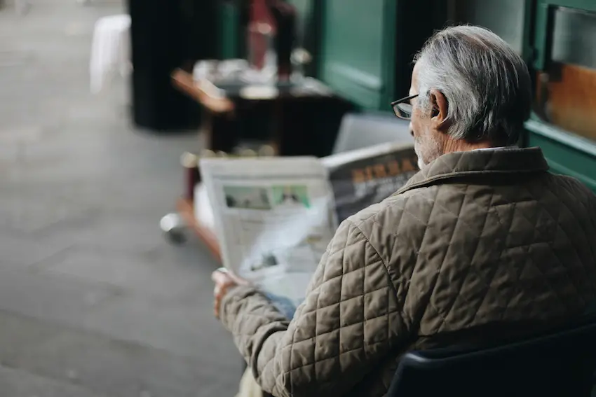 Un anciano leyendo el periódico en un café.