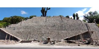 A pyramid surrounded by ladders and scaffolding sits right next to a highway