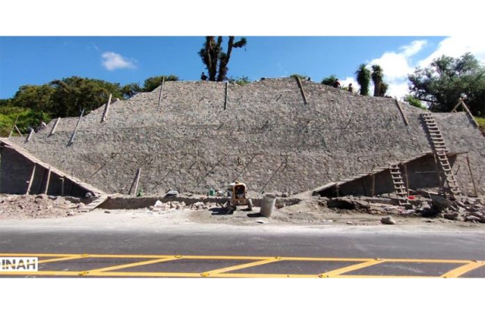 A pyramid surrounded by ladders and scaffolding sits right next to a highway