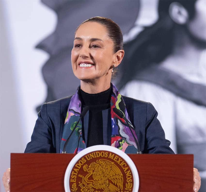 Mexican President Claudia Sheinbaum stands at a podium smiling