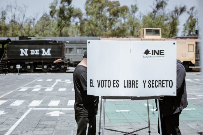 A Mexican voter fills out a ballot in a voting booth bearing the words 