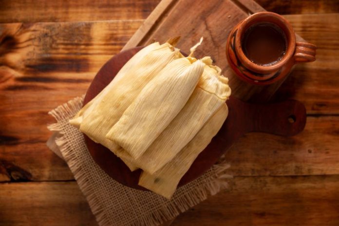 Tamales served on a plate with (possibly) champurrado.