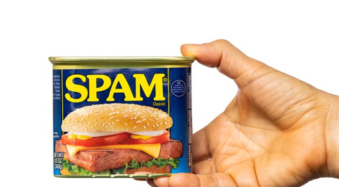 A hand holds a can of spam