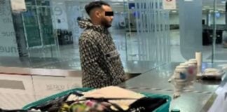 A man stands by an open suitcase in an airport revision area