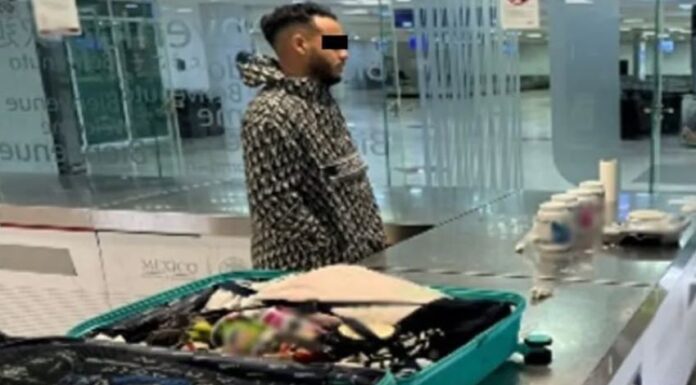 A man stands by an open suitcase in an airport revision area
