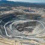 An large open-pit mine in an arid area with mountains in the background