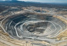 An large open-pit mine in an arid area with mountains in the background