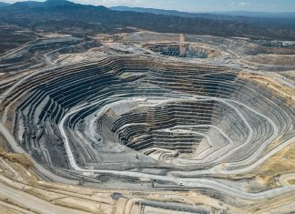 An large open-pit mine in an arid area with mountains in the background