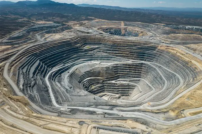 An large open-pit mine in an arid area with mountains in the background