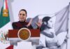 Claudia Sheinbaum at a press conference, standing behind the presidential podium, gesturing with both hands parallel in front of her, as if to show the size of something.