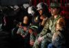 Mexican soldiers and firefighters in a military plane in uniform and firefighting gear awaiting takeoff to fight fires in Los Angeles.