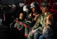 Mexican soldiers and firefighters in a military plane in uniform and firefighting gear awaiting takeoff to fight fires in Los Angeles.