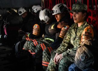 Mexican soldiers and firefighters in a military plane in uniform and firefighting gear awaiting takeoff to fight fires in Los Angeles.