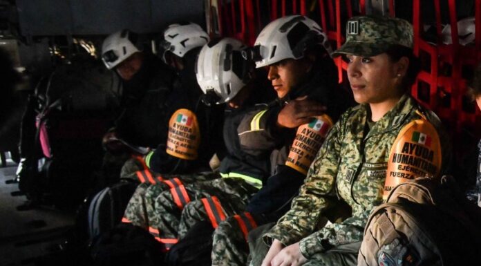 Mexican soldiers and firefighters in a military plane in uniform and firefighting gear awaiting takeoff to fight fires in Los Angeles.