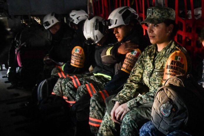 Mexican soldiers and firefighters in a military plane in uniform and firefighting gear awaiting takeoff to fight fires in Los Angeles.