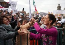 President Claudia Sheinbaum shakes hands with the crowd during her 100-day address in Mexico City