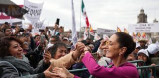 President Claudia Sheinbaum shakes hands with the crowd during her 100-day address in Mexico City