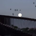 A full moon rises over the Mexico-U.S. border wall
