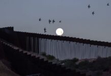 A full moon rises over the Mexico-U.S. border wall