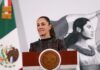 Mexico's President Claudia Sheinbaum standing at the presidential podium in the National Palace during a press conference.