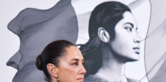 Side profile photo of Mexican President Claudia Sheinbaum at a press conference, standing in a parallel position to her admnistration's logo, a illustration in profile of a young Mexican Indigenous woman standing in front of the Mexican flag