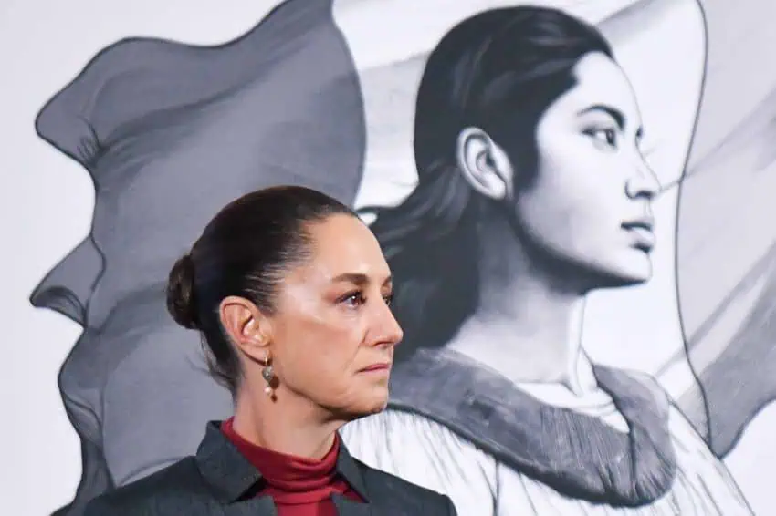 Side profile photo of Mexican President Claudia Sheinbaum at a press conference, standing in a parallel position to her admnistration's logo, a illustration in profile of a young Mexican Indigenous woman standing in front of the Mexican flag