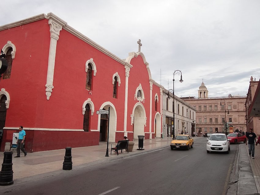 Guadalupe Victoria Street in downtown Saltillo, Coahuila, Mexico. You can see the red-fronted San Esteban Parish and the Plaza de la Nueva Tlaxcala, the Government Palace and a tower of the Cathedral in the background.