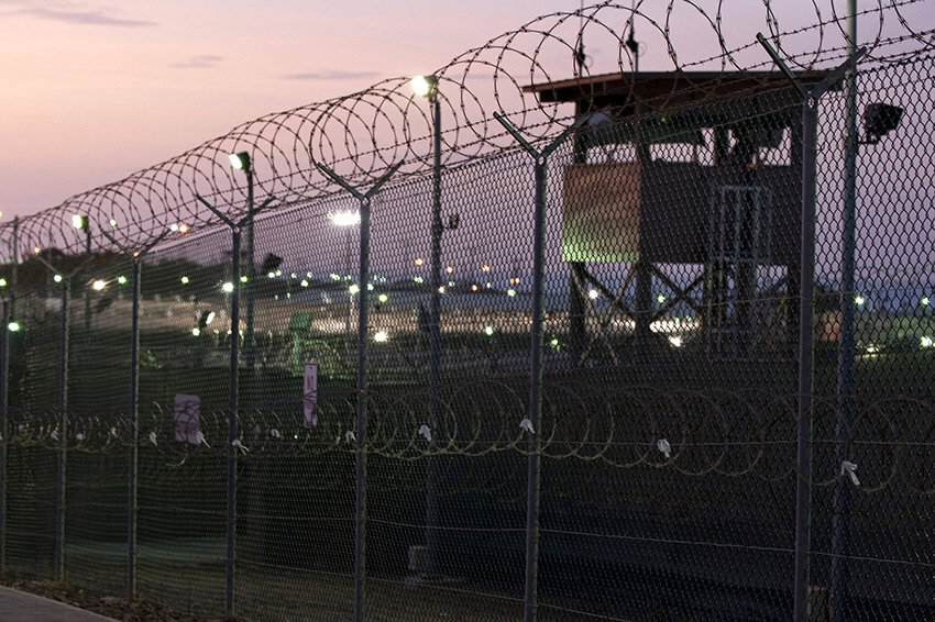 A guard tower behind a barbed wire fence at Guantanamo Bay