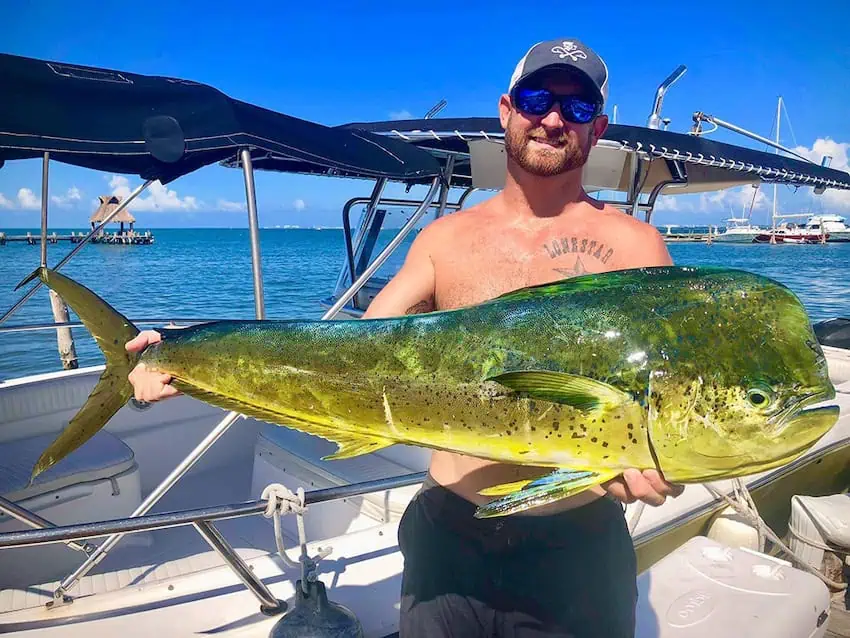 A man holding an enormous fish he just caught near Cancún