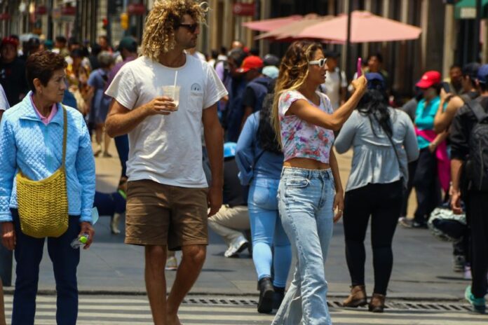 National and foreign tourists visit the Zócalo on this warm and semi-empty Sunday