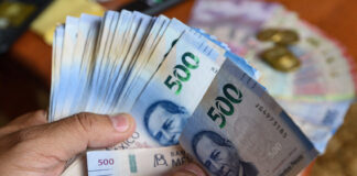 Hands fan out a large number of Mexican 500-peso bills