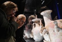 Two gray-haired people look at large ceramic vases in a museum display case at the National Museum of Anthropology, Mexico City's most popular museum in 2024.