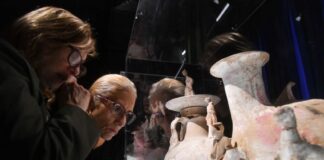 Two gray-haired people look at large ceramic vases in a museum display case at the National Museum of Anthropology, Mexico City's most popular museum in 2024.