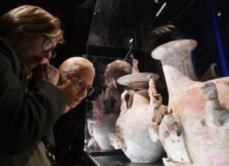 Two gray-haired people look at large ceramic vases in a museum display case at the National Museum of Anthropology, Mexico City's most popular museum in 2024.