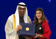 A man wearing a ghutra head covering presents the Zayed environmental award to a young Mexican woman