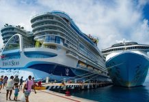 A massive cruise ship towers over a dock in Cozumel, Mexico while passengers cue to board